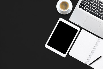 Office black work desk table with laptop, tablet, cup of coffee and blank note book.