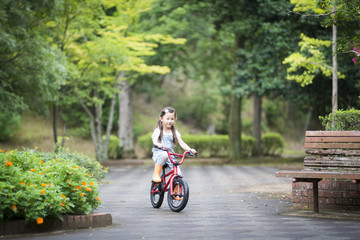 Fototapeta premium Happy little girl riding a red bicycle