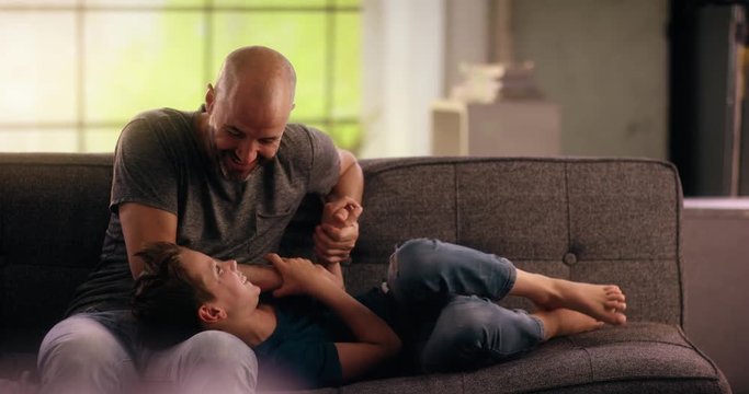 Father tickling his son on the couch