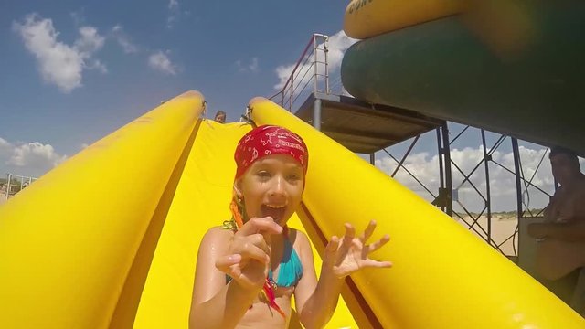 Child on water slide at aquapark. Summer holiday.