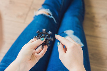 Girl teenager in holey jeans holds in hands and plays with spinner