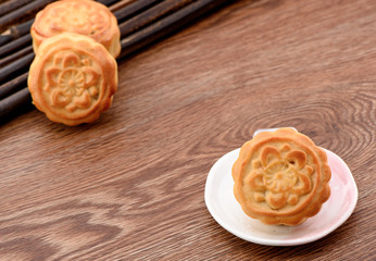 Chinese moon cake -- food for Chinese mid-autumn festival on a white plate isolated on wooden background