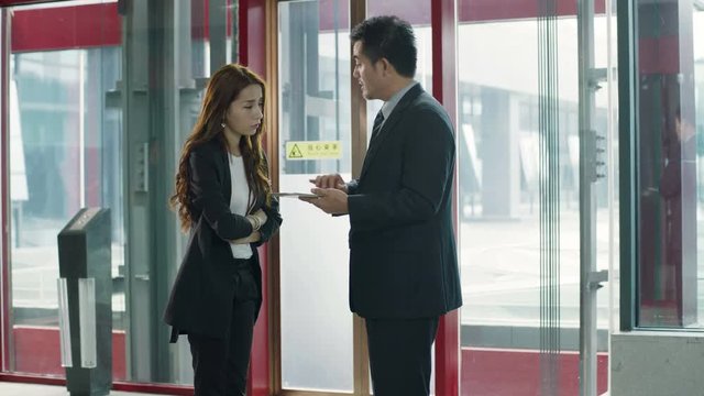 asian corporate executive giving instruction to female subordinate in company lobby