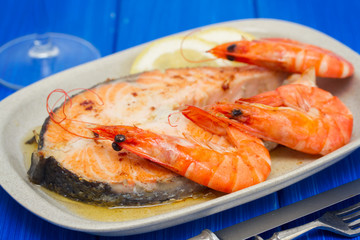 fried salmon with shrimps on white dish on wooden background