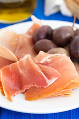 jamon with olives on white plate