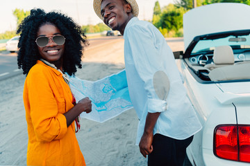 smiling african american couple choosing destination on map while traveling together