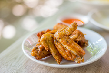 Plate of fried chicken wings on wooden table, Thai food.