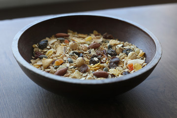 Muesli with nuts and tropical dried fruits. Healthy breakfast: flakes cereal in wooden plate.