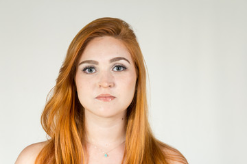 Portrait of serious teenager. She is white, red-haired and young..