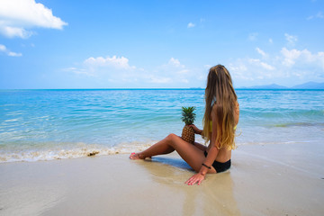 Pefect Vacation. Summer travel. Young beautiful model holding Pineapple relaxing on the beach in sunny day