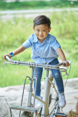 Obraz premium Asian boy sitting on an ancient bicycle.