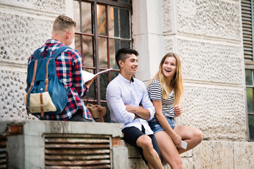 Group of students in front of university studying, having fun.