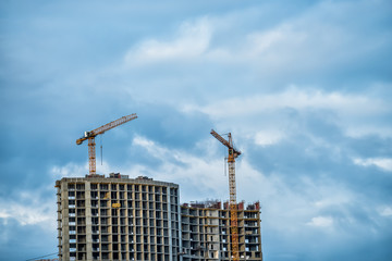 Fototapeta premium Unfinished high-rise buildings and cranes against the sky 