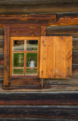 The window with the wooden carved architrave in the old wooden house in the old Russian town.