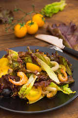 Fresh mix salad with shrimps, yellow cherry tomatoes and balsamic sauce. on wooden background. Close-up. Top view