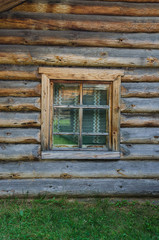 The window with the wooden carved architrave in the old wooden house in the old Russian town.
