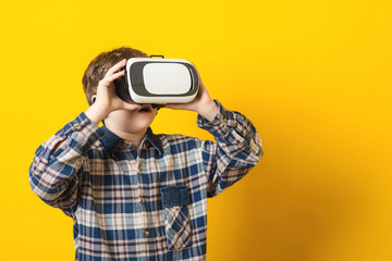 The boy wearing virtual reality goggles over yellow background.