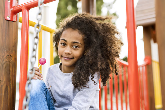 African American Girl On Playground Eating Lollipop.