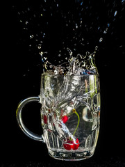 Water splash close-up macro of the cherry as it plunges into the glass of water.