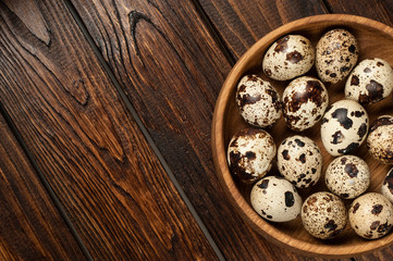 Fototapeta premium top view on quail eggs in wooden plate over old wooden background