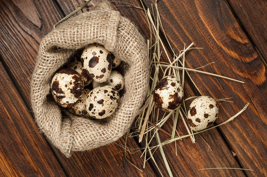 top view on quail eggs in burlap sack over old wooden background