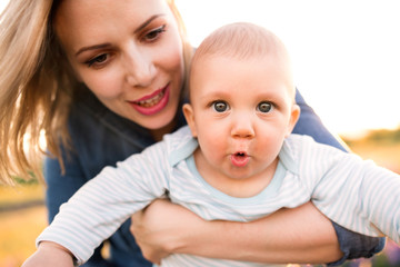 Young mother in nature with baby son in the arms.