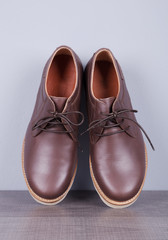 Brown leather men's shoes on a wood and wall background