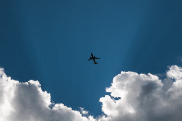 the silhouette of the plane against the sky and clouds,