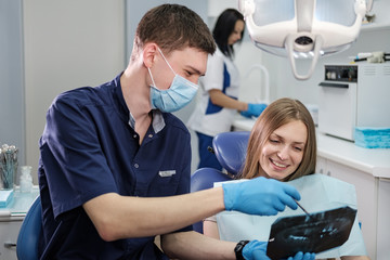 Doctor dentist man shows to patient girl x-ray