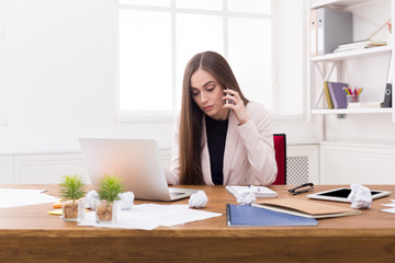 Serious business woman at work talking on phone