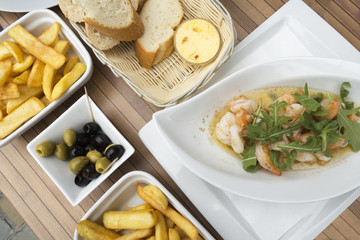 Fried prawns, french fries, olives, bread, butter on the table