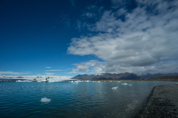 Iceland - Cloud front over glacial lake with black sand beach