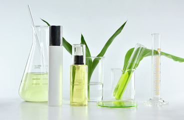 Cosmetic bottle containers with green herbal leaves and scientific glassware, Blank label package...