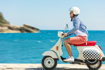Handsome man posing on a scooter in a vacation context. Street fashion and style. © FS-Stock