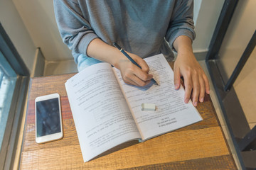 Overhead view of woman hand doing homework in library