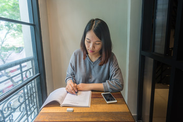Young student writing note, take note, doing homework on book