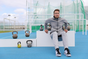 Gym fitness man training arms muscles doing triceps dips at outdoor training center at stadium....