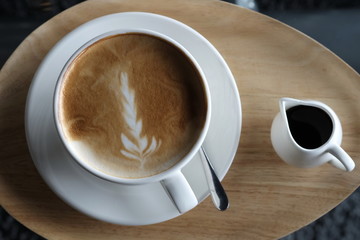 Latte coffee in white glass on a wooden tray is served on the table,viewed from above.