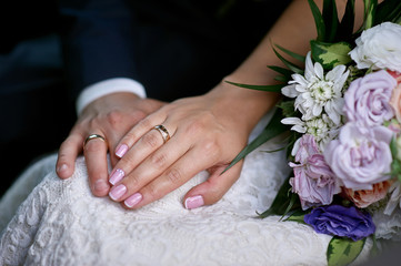 Obraz na płótnie Canvas Hands of the bride and groom near the wedding bouquet for a walk