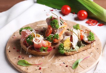 Bruschetta sandwich with ham, herbs and tomatoes on round board