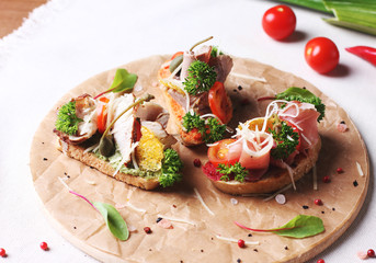 Bruschetta sandwich with ham, herbs and tomatoes on round board