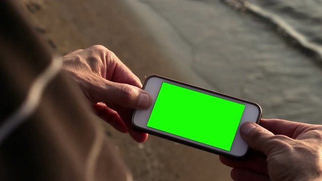 Generic phone with green screen corner pin on the beach in summer