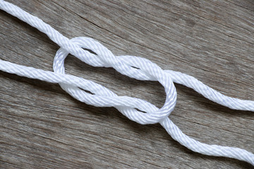 White rope in reef knot shape on wood background