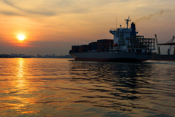 Obraz premium Cargo ship sailing on river at sunrise