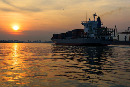 Cargo ship sailing on river at sunrise