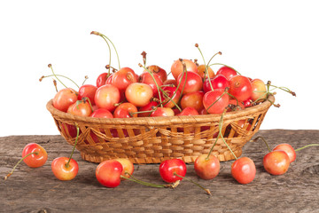 Yellow cherry in a wicker basket on a wooden table with a white background