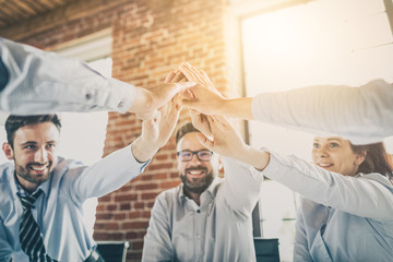 Happy business team giving high five in office.