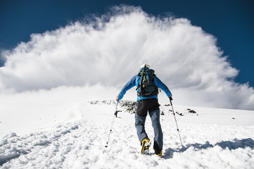 Fototapeta na wymiar Mountaineer rises uphill to meet a mountain storm coming from the mountain