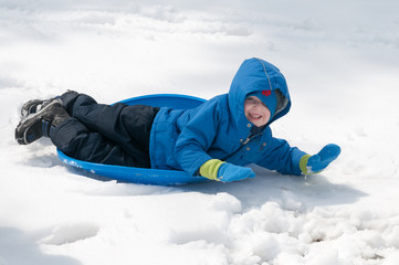Fototapeta na wymiar Young little boy enjoying sledding outside on a snow day