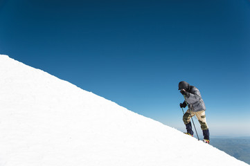 The climber climbs the snow-covered summit.